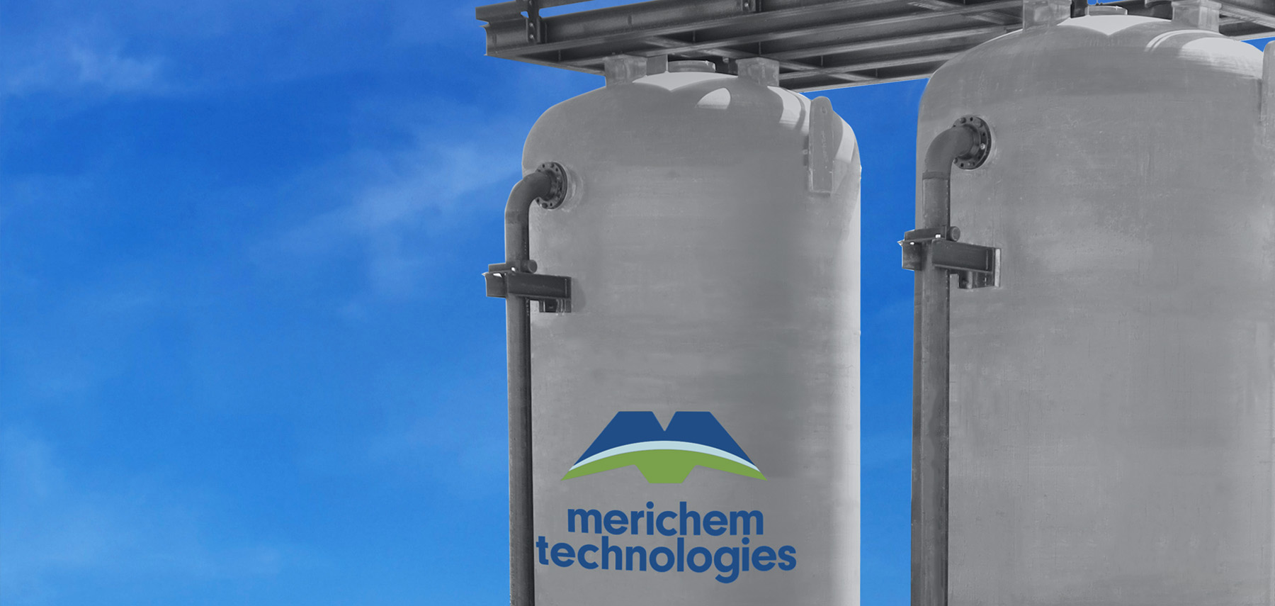 top of vertical lead/lag vessels with platform and Merichem Technologies blue and green logo against blue sky