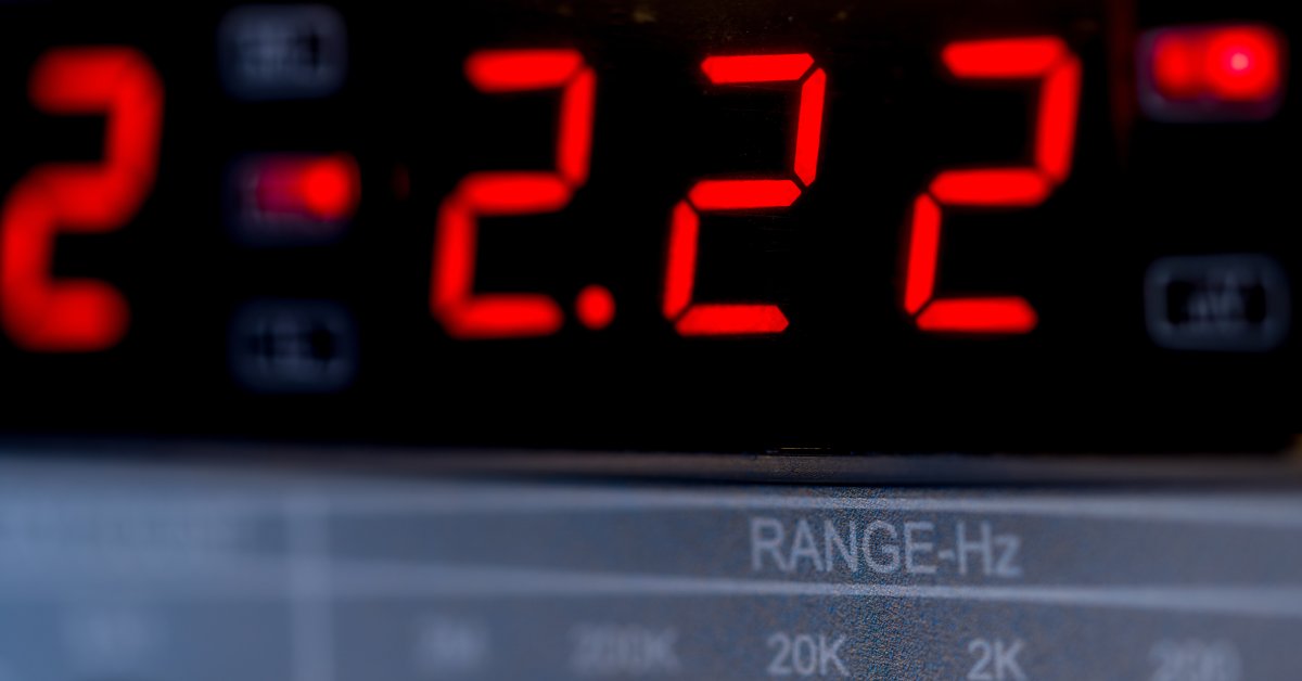 A digital hygrometer that measures humidity displays 2.22 on a black screen with red analog numbers.