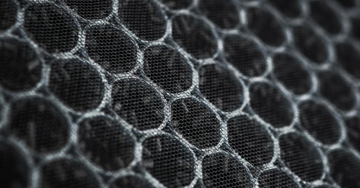 A close-up of an activated carbon filter. It consists of many coils with a mesh covering and small particles caught in it.