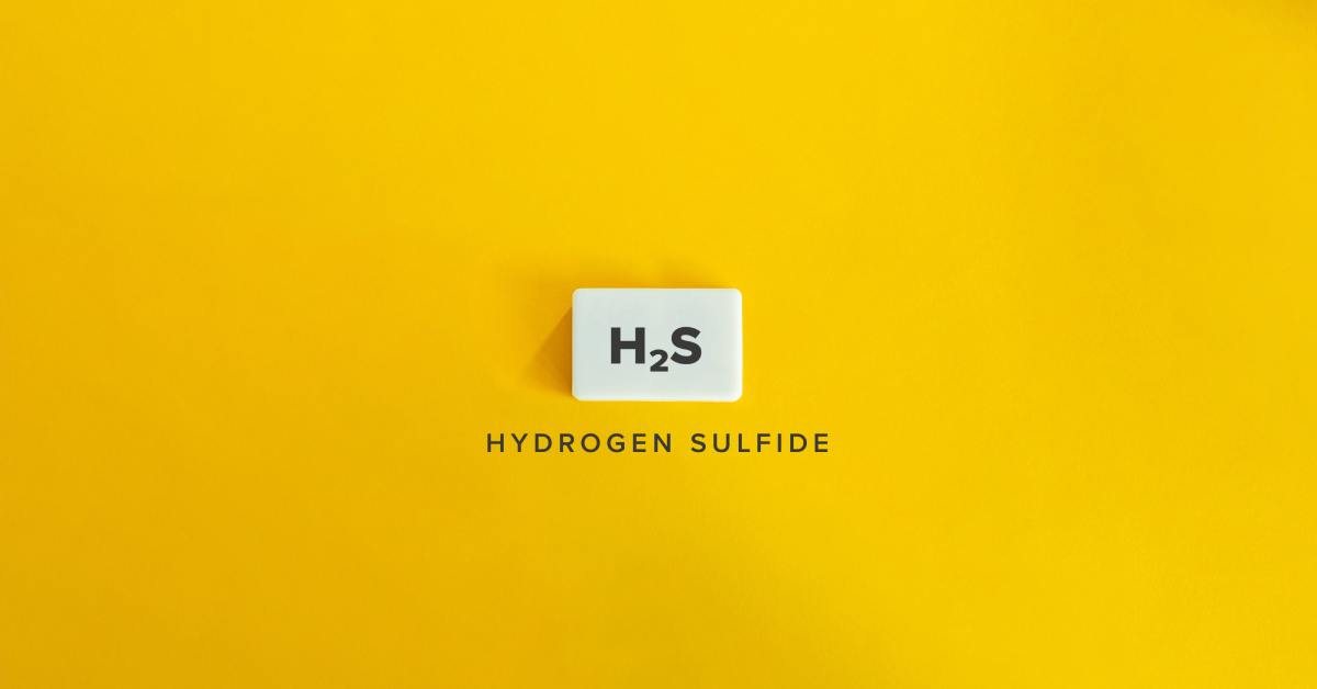 The chemical formula, H2S, written on a white tile above the words "HYDROGEN SULFIDE" on a yellow background.