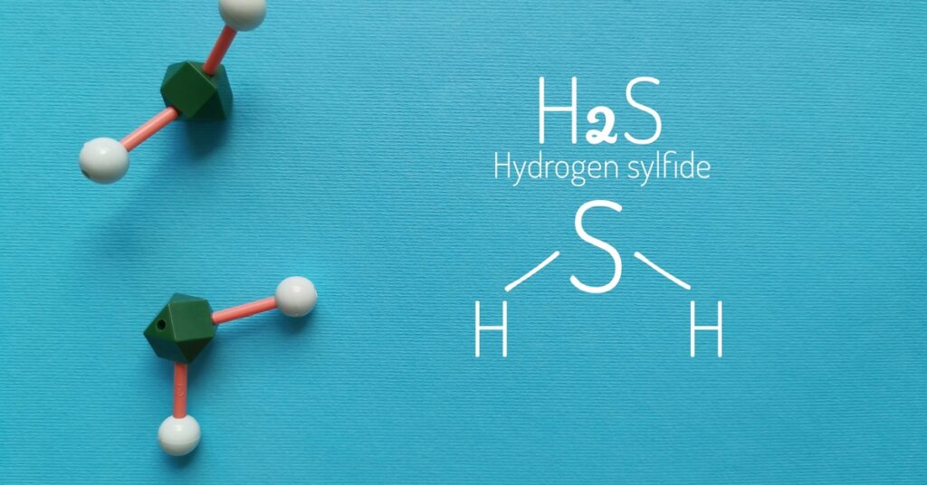 The chemical formula of hydrogen sulfide written in white against a blue background next to models of hydrogen sulfide.