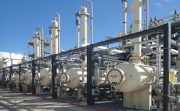 FIBER FILM Contactor units for treating sulfur lined up at a facility with perspective diminishing to the left against a blue sky