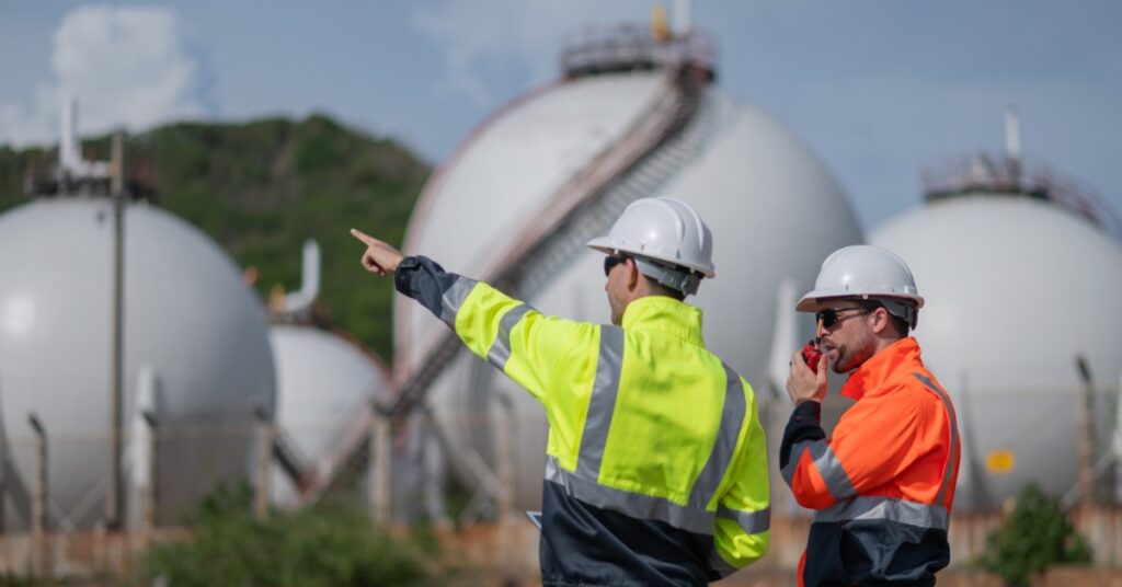 A close-up of two engineers at an industrial gas site balancing development and environmental impact.