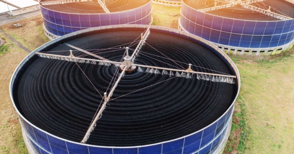 Four identical circular biofilter tanks installed outside in a field at a wastewater treatment plant.