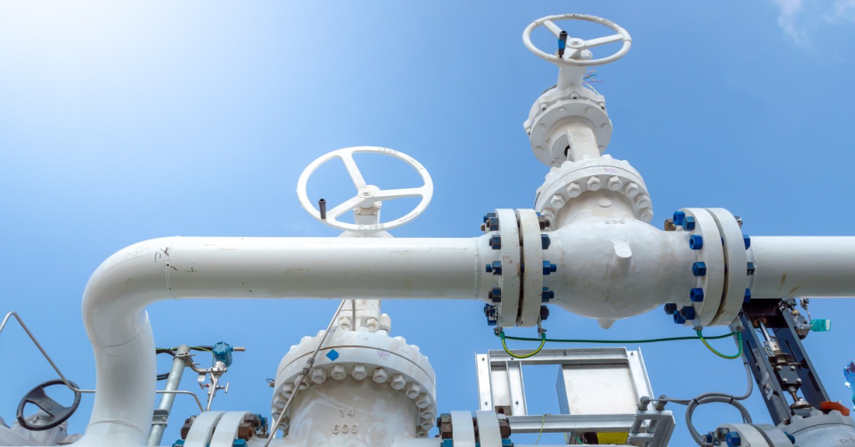 White industrial pipeline with large bolted valves and handwheel controls against a bright blue sky. White industrial pipeline with large bolted valves and handwheel controls against a bright blue sky.